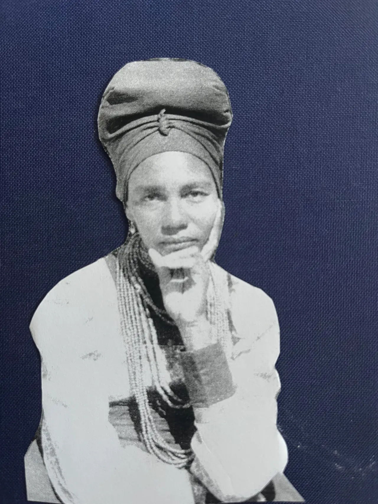 Adelheid Mbwaondjou wearing a headwrap, with one hand against her cheek.